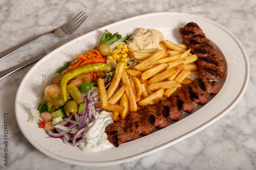 Photography Turkish food dish. Adana kebab with hummus chips and salad.