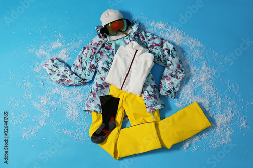 Stylish winter sport clothes on light blue background, flat lay