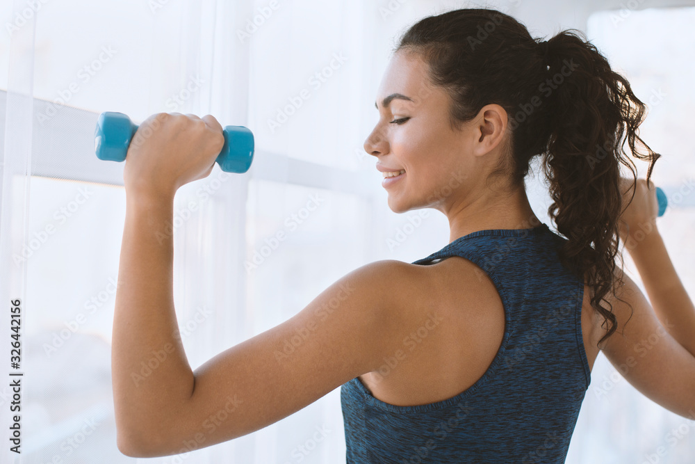 Sporty Hispanic girl on training with dumbbells in gym Sporty Hispanic girl on training with dumbbells in gym