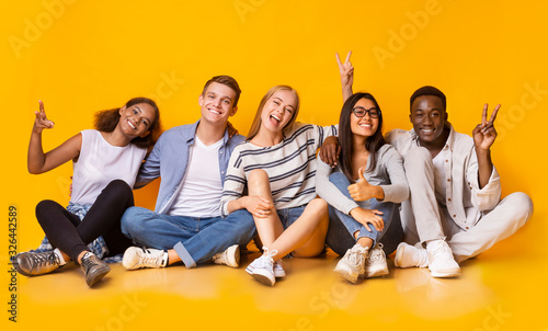 Carefree teenagers having fun over yellow studio background