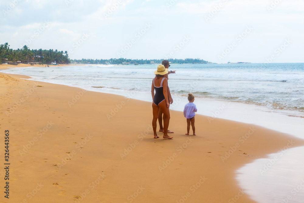 A woman with child by the hand goes along the sea shore