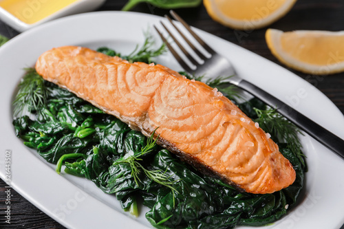 Tasty salmon with spinach on plate, closeup