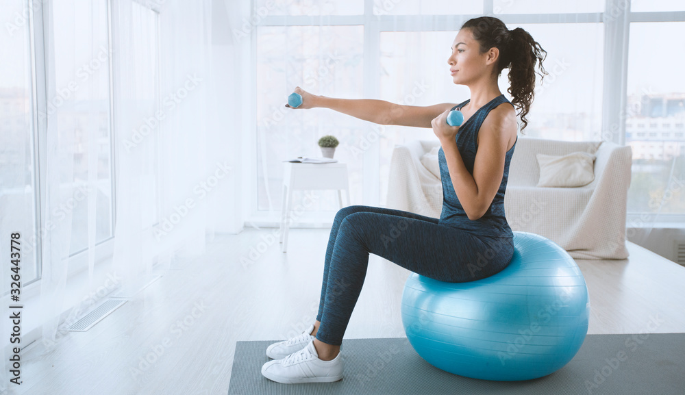 Young woman with gym ball and dumbbells at home, blank space - obrazy, fototapety, plakaty 