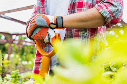 Close up of gardener wearing gloves while holding shovel in garden shop