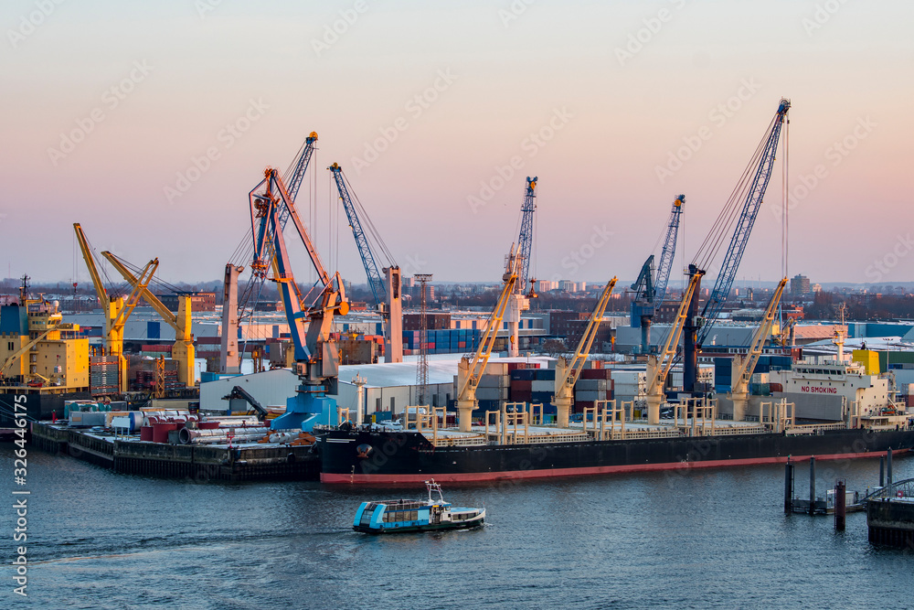 Entladener Frachter mit Kränen im Hamburger Hafen in der Abenddämmerung