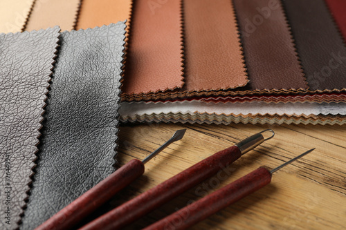 Leather samples and tools on wooden table, closeup
