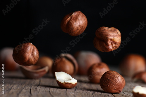 tossed hazelnuts falling on a wooden table