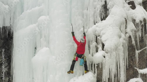 Lone climber resting before ascending frozen cliff face Mount Kineo 4K photo