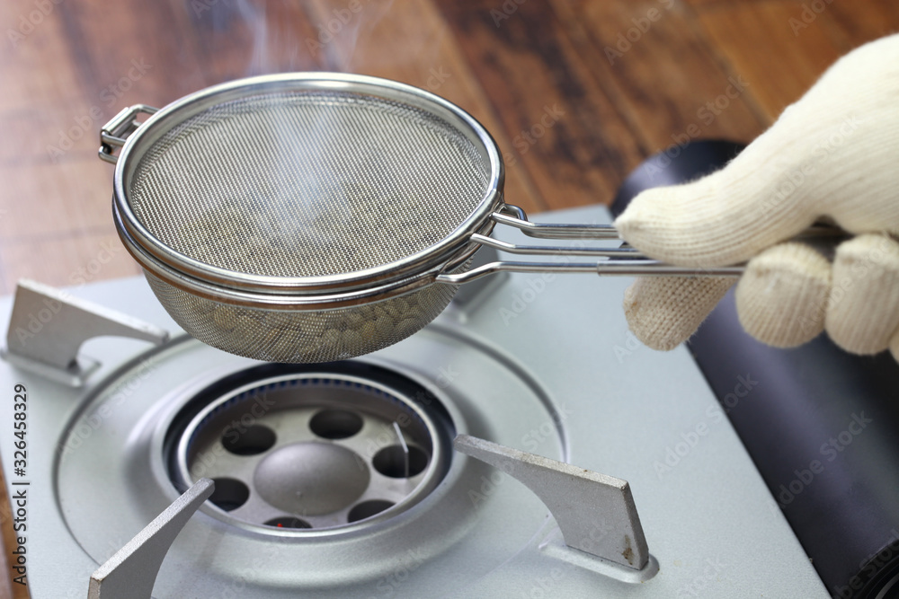 roasting coffee beans process by handy roaster at home; shaking handy roaster over portable gas