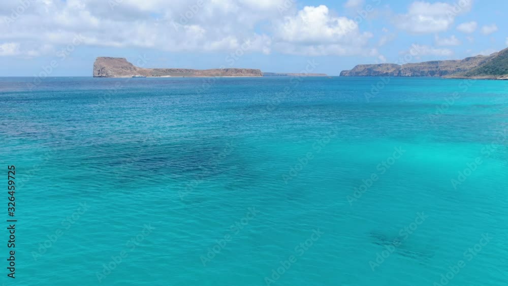 Approaching Gramvousa beach near Balos Beach in Crete Greece with blue turquoise-colored water and rocky isles, Aerial flyover shot Approaching Gramvousa beach near Balos Beach in Crete Greece with blue turquoise-colored water and rocky isles, Aerial flyover shot