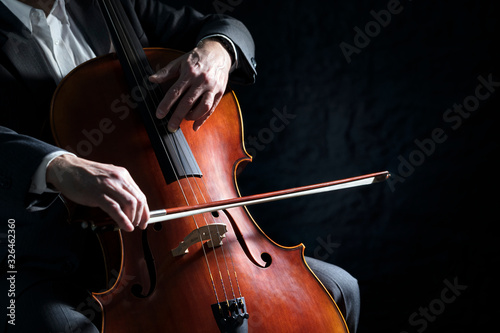 Cello player or cellist performing in an orchestra background