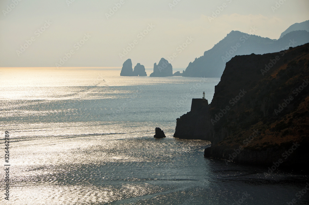 Punta Campanella seen from the sea, in the background the island of Capri and the faraglioni. Amalfi coast, Italy