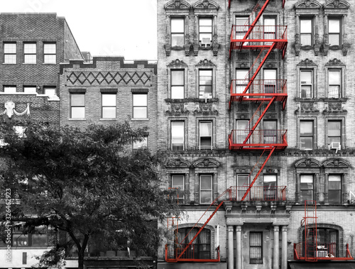 Fotografia Red fire escape on the exterior of an old building in black and white - Manhatta