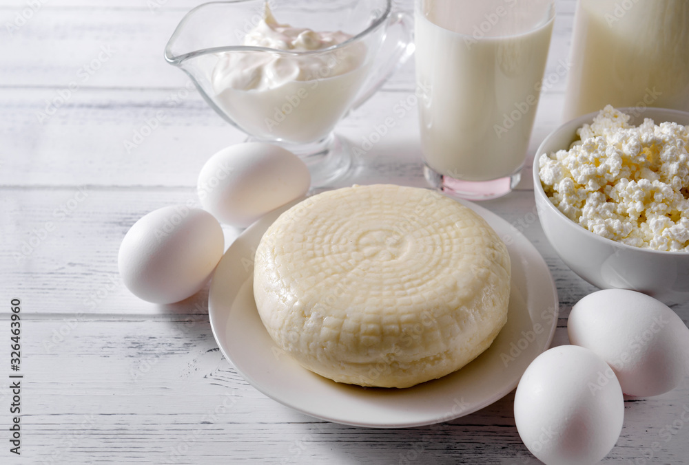glass of milk, a bottle of milk, several raw eggs, cottage cheese, cheese, sour cream on a light wooden glass of milk, a bottle of milk, several raw eggs, cottage cheese, cheese, sour cream on a light wooden