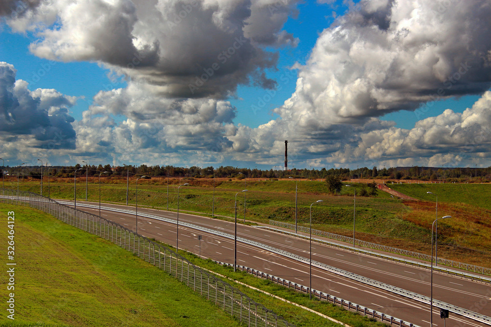 Asphalt highway among the landscape under the sky in cumulus clouds