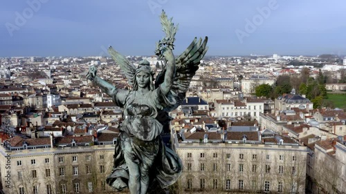 The Liberty Angel of Girondins monument with the city of Bordeaux, France in the background, Aerial orbit reveal shot photo