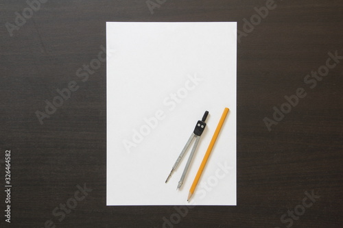 Template of white paper, divider and pencil on dark wenge color wooden background.