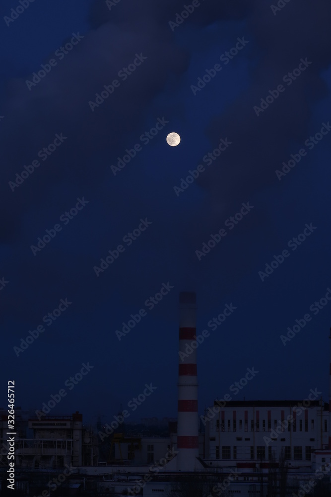 Factory chimneys smoke in the moonlight