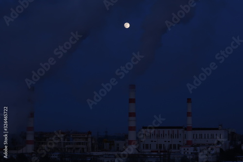 Three factory chimneys smoke at night