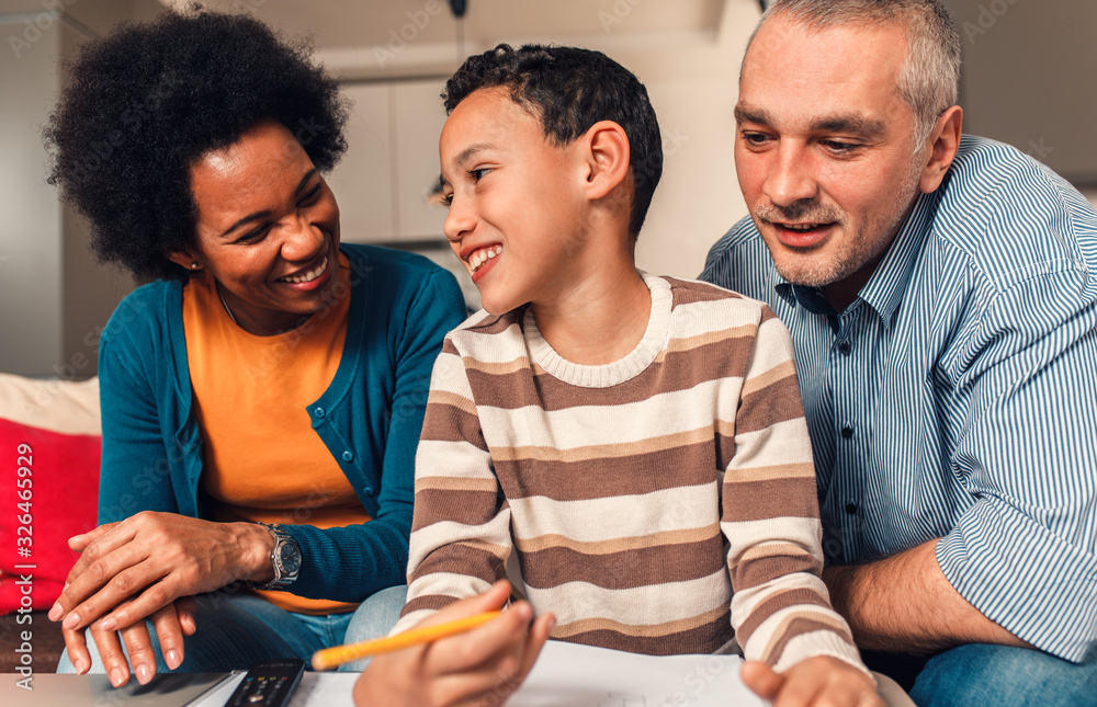 Parents helping their son with his homework at home in living room. Parents helping their son with his homework at home in living room.