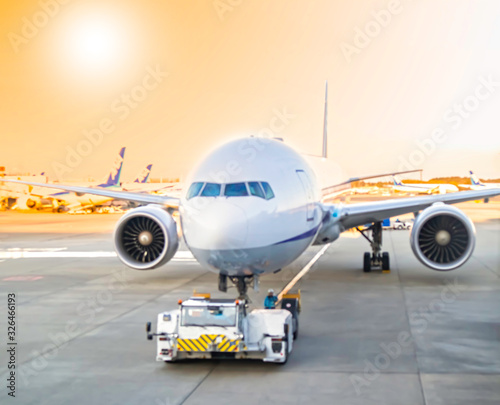 Airplane with towing truck pushing in parking place at the International airport, blurred photo,solft focut,travel,transportation concept.