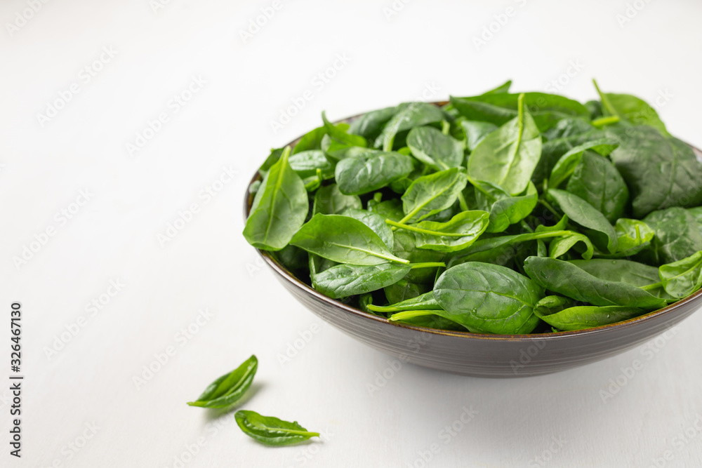 Fresh spinach leaves in a bowl on a white background Fresh spinach leaves in a bowl on a white background