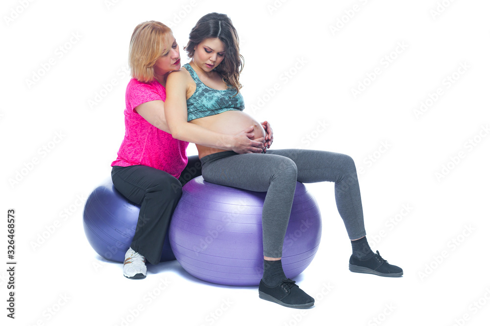 Young pregnant woman exercising with physiotherapist in birthing school. Doctor's help conceptat in antenatal class. Isolated white background. Young pregnant woman exercising with physiotherapist in birthing school. Doctor's help conceptat in antenatal class. Isolated white background.