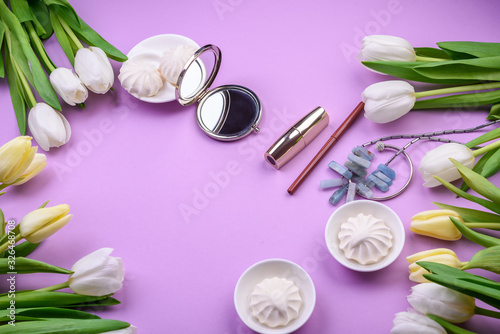  white tulips and cosmetics, sweets on pink background. Flat lay. womanlike desk with cosmetics, lipstick and white flowers on pink background.