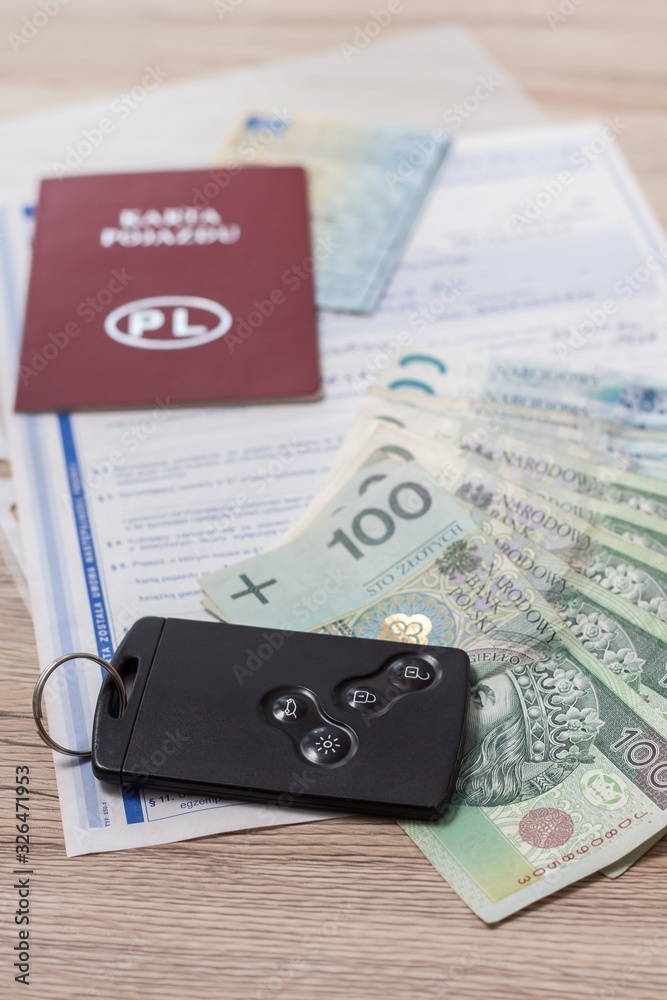 Umowa zakupu auta leży na stole. Banknoty PLN i karta do auta leżą na dokumentach zakupu.