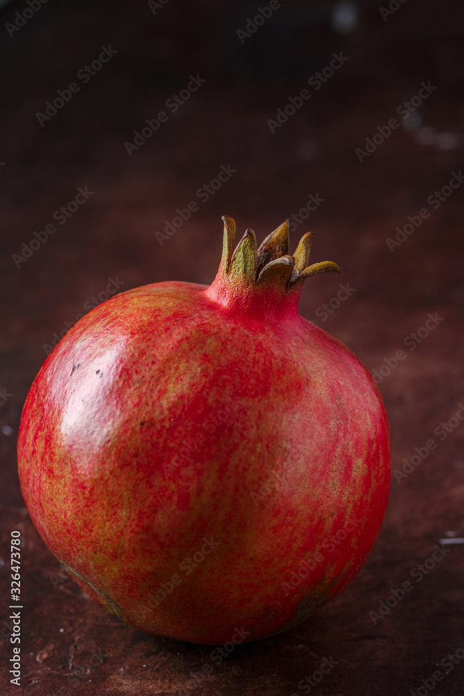 Ripe juicy organic whole pomegranate on a dark background. Fresh fruit. Vitamins. Healthy diet. Selective focus, copy space
