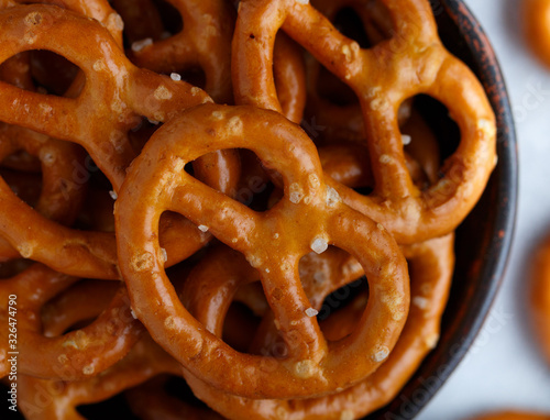 Mini pretzels with salt in a ceramic bowl close-up. Beer appetizer on a gray background. Selective focus, top view