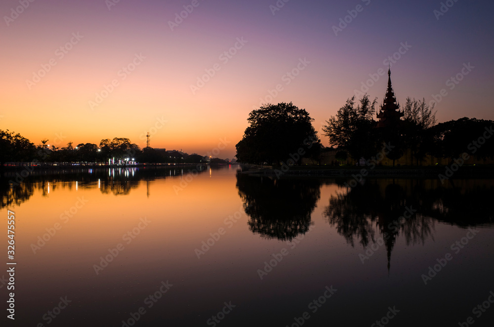 Mandalay Palace wall with reflection in moat, picturesque silhouette with twilight sky in sunset, Myanmar