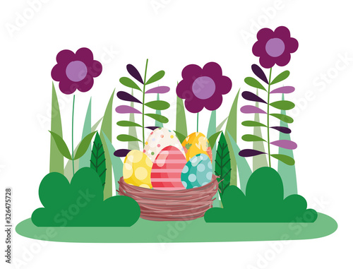 happy easter whisker basket with decorated eggs on grass with flowers