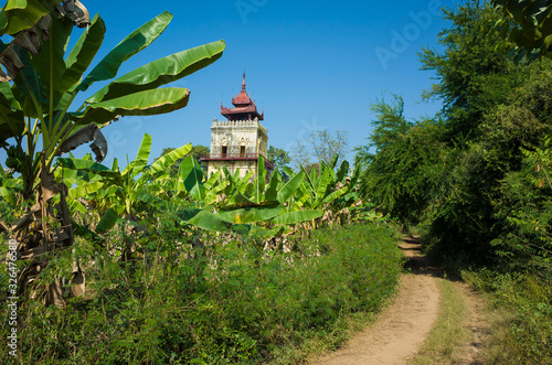 Nan Myint Watch Tower, is the only surviving structure of King Bagyidaw's royal palace at Inwa (Ava) in Myanmar. Rural road along banana plantation and burmese traditional architecture photo