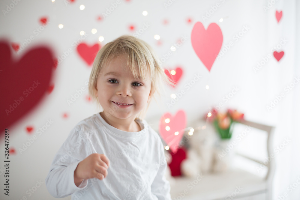 Cute blonde toddler boy, holding box in heart shape and flowers Cute blonde toddler boy, holding box in heart shape and flowers