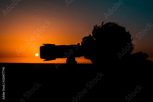 silueta de un hombre sujetando una cámara de fotos al amanecer