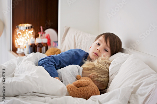 Sick children, boy brothers, lying in bed with a fever, resting