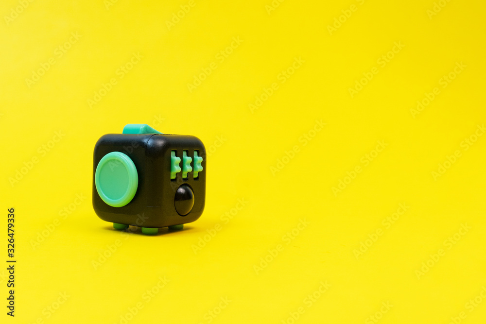 Black and green fidget cube on yellow background, minimal concept, copyspace.  - obrazy, fototapety, plakaty 