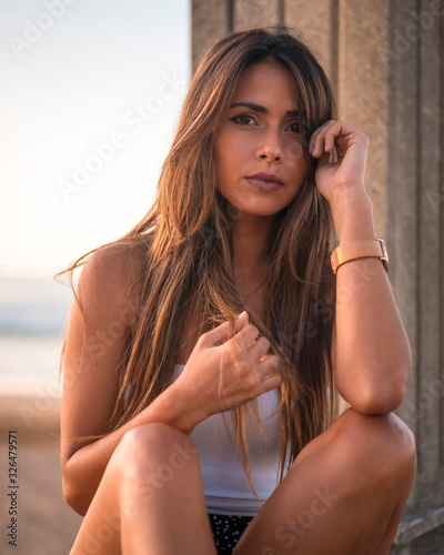 Seductive look of a brunette on a summer afternoon sitting with sea in the background