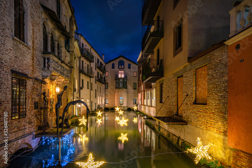 Fototapeta Naklejka Na Ścianę i Meble -  27 december 2019, Treviso (Italy): Statue and star lights on the Malvasia Canal in the city center of Treviso at sunset