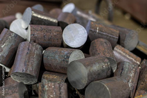 a pile of raw steel short rods cutted by saw- workpieces prepaired for forging, close-up with selective focus photo