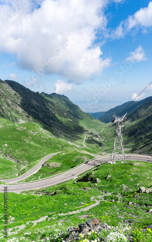 Top vew of winding road in mountains, and power networks. Summer coming in mountains