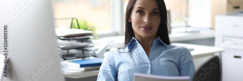 Canvas Print Portrait of attractive lady in classic clothes sitting on chair near computer and putting feet on table