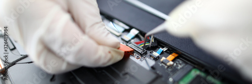 Focus on fixing wires in pc. Technician wearing gloves repairing personal computer using tweezers. Technical support of gadgets and devices restoring productivity of electronics photo