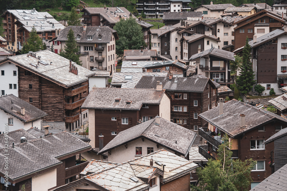 View of the roofs of chalets in a Swiss resort. A place preserving authentic architecture. Natural stone roofs, wooden facades