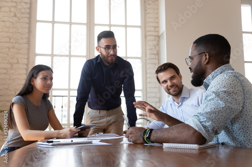 Middle eastern ethnicity employee listens african colleague during group meeting