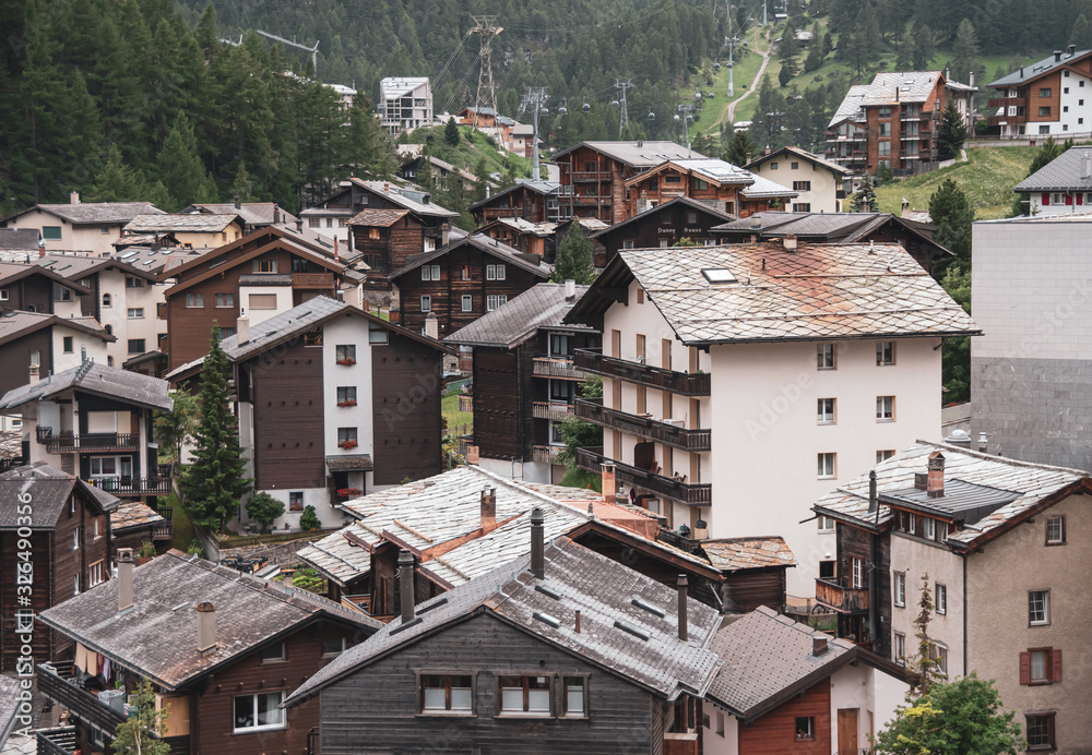 View of the roofs of chalets in a Swiss resort. A place preserving authentic architecture. Natural stone roofs, wooden facades. Zermatt, Switzerland.