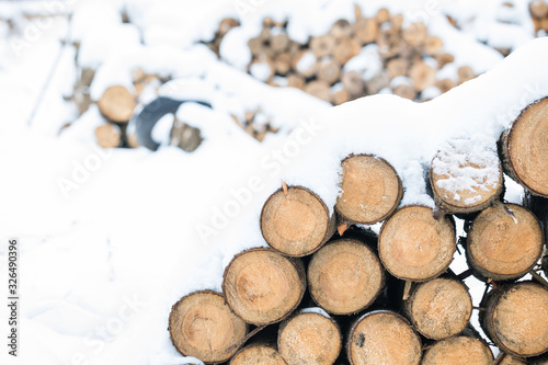 Pile of wooden logs under snow in winter  background  selective focus  toned