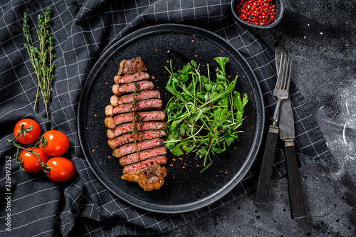 Fillet entrecote steak, marbled beef meat with arugula. Black background. Top view