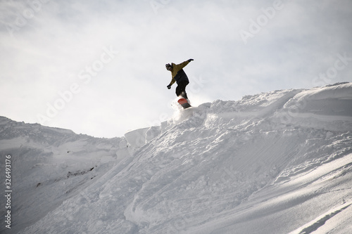 Freerider in anorak jumping on a snowboard in mountains © fesenko